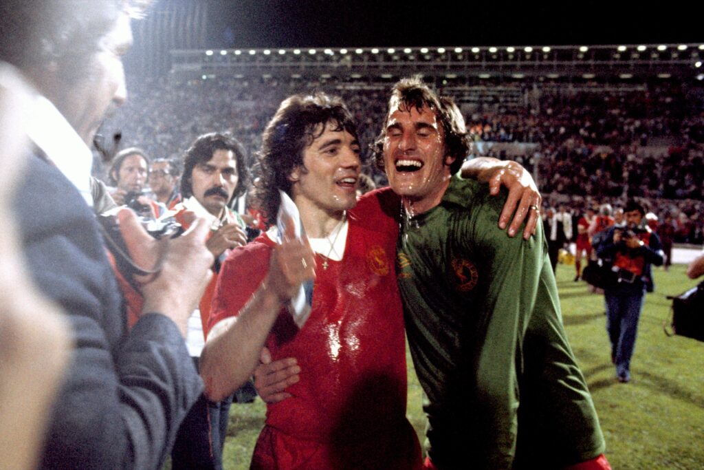 Two Liverpool players celebrate on the pitch in the 1970s, the club's European Cup era.